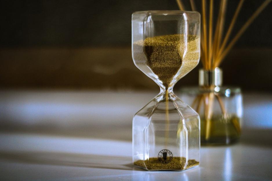 Hourglass casting shadows with reed diffuser in background