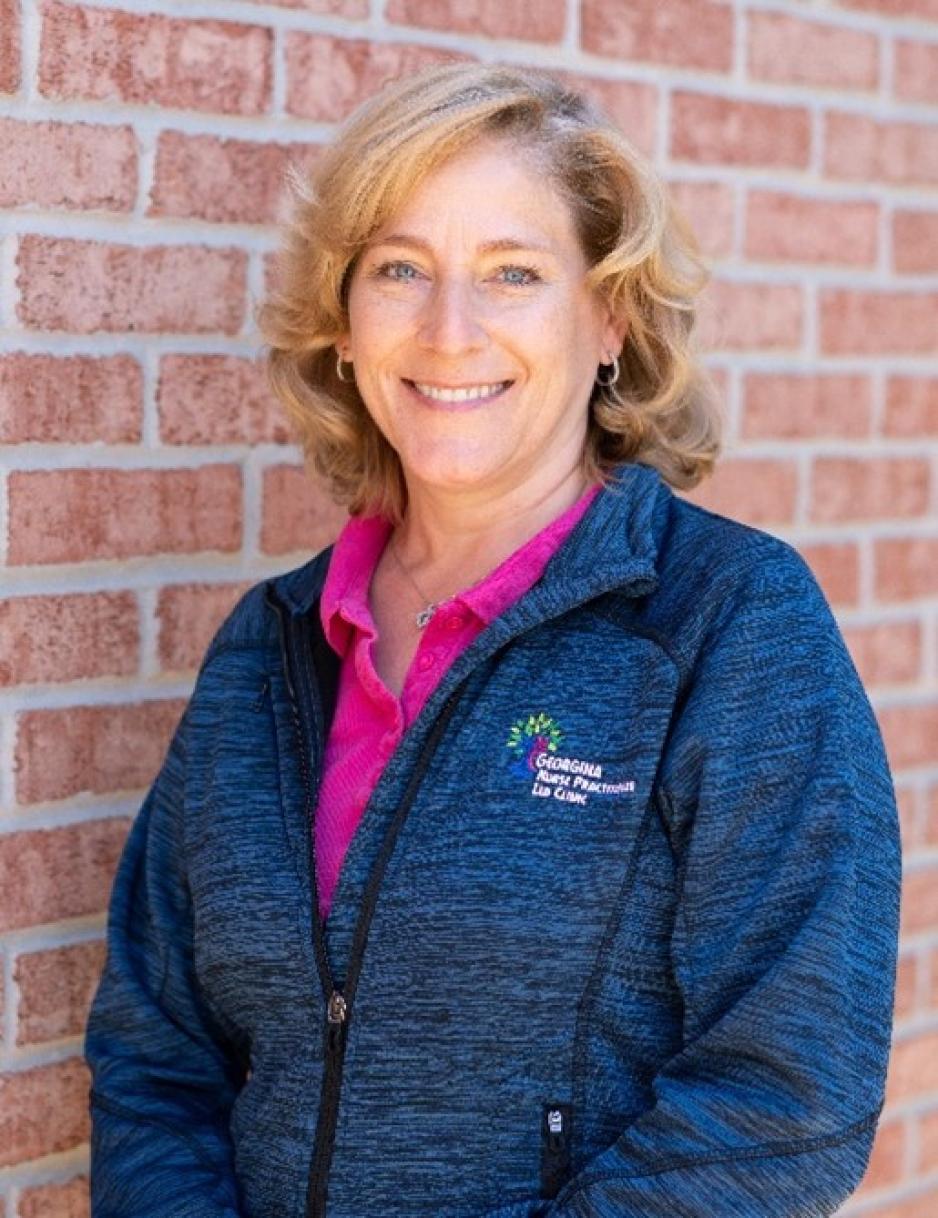 Beth Cowper-Fung stands smiling in front of a brick wall.