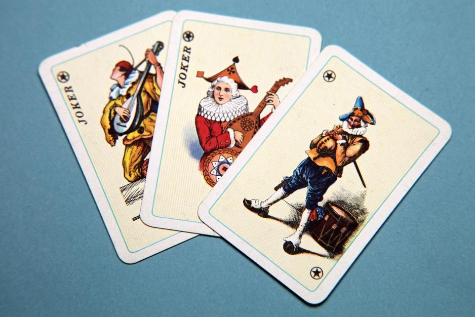 Three vintage playing cards with jokers in different outfits